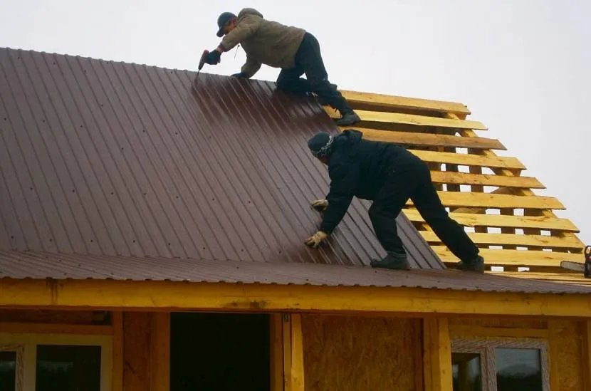 Montaż arkuszy tektury falistej na dachu budynku gospodarczego