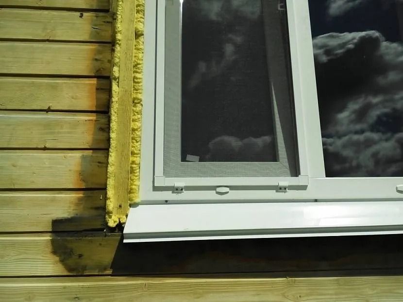Szczelina między ramą okienną a ścianą domu wypełniona jest pianką poliuretanową