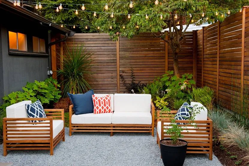 Małe patio z płotem z naturalnego drewna, sofami i fotelami