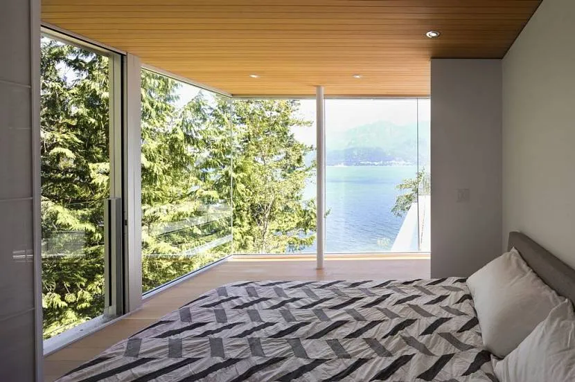 Sypialnia z widokiem na jezioro i las za oknem wprowadza romantyczny nastrój